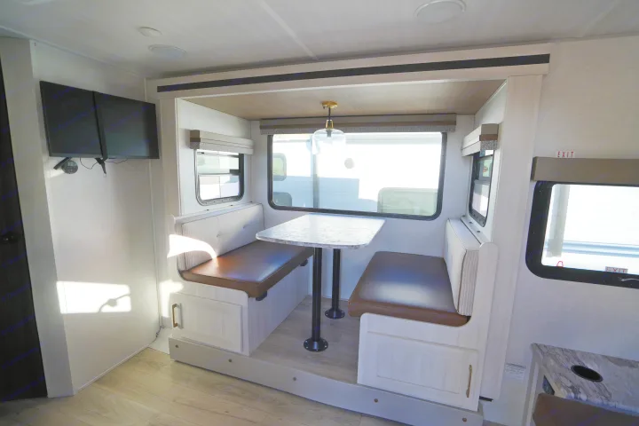 RV rental: Modern, bright interior featuring a cozy dinette with comfortable benches, a table, and dual wall-mounted monitors.. Forest River Surveyor Legend 2024