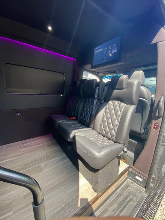 Luxurious RV rental interior with quilted leather seats, an entertainment screen, and purple ambient lighting for comfort.. Mercedes-Benz Sprinter 2022