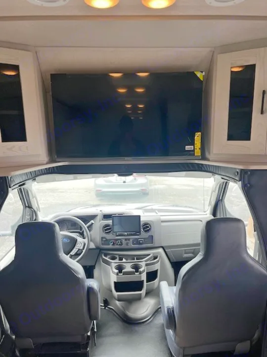 RV rental interior: Cockpit with large overhead TV, driver and passenger seats, and Ford dashboard.. Nexus Viper 2026