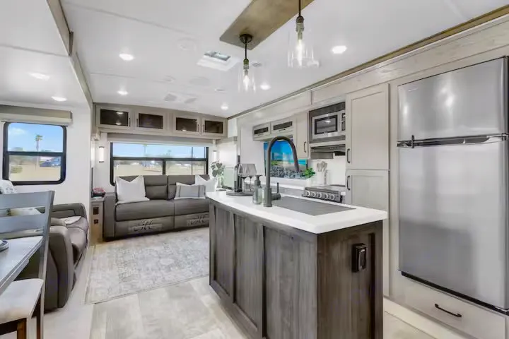 Bright rv rental interior showing a modern kitchen with island and comfortable living area. Great for travel.. Forest River Flagstaff Classic 2024