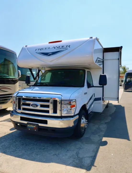 White Coachmen Freelander Class C motorhome, ideal for rv rental, parked on a sunny lot with its slide-out extended.. Coachmen Freelander 2023