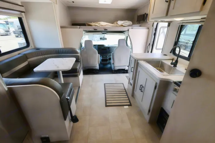 Spacious and bright rv rental interior, featuring a comfortable dinette, functional kitchen, driver's cab, and overhead bunk.. Coachmen Freelander 2023