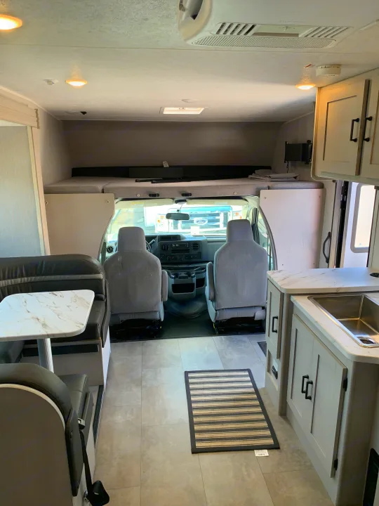 Spacious RV rental interior with dinette, kitchen, and cab-over bunk visible from the living area.. Coachmen Freelander 2023