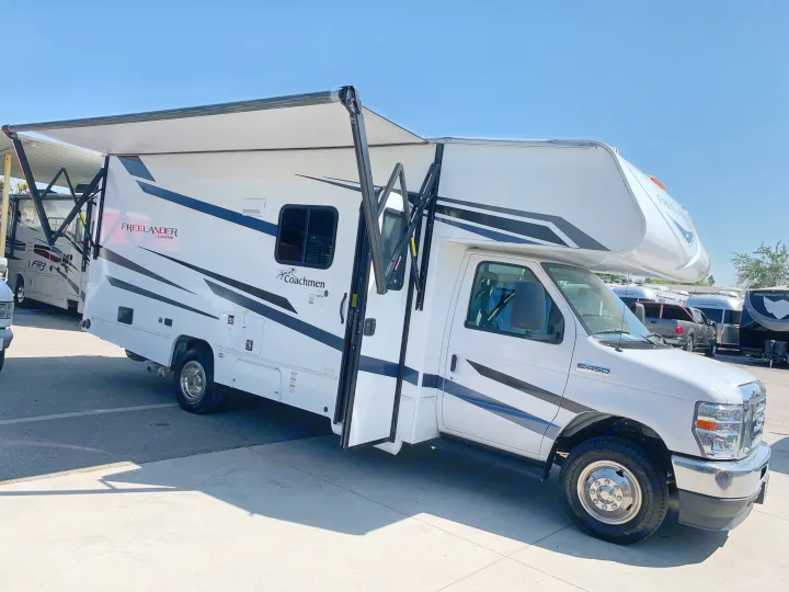 A white Coachmen Freelander Class C motorhome with its side awning extended, available as an rv rental for outdoor adventures.. Coachmen Freelander 2023