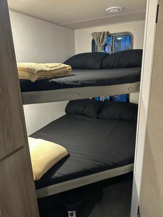 Cozy bunk beds inside an rv rental, featuring black sheets and pillows, ideal for a comfortable family getaway.. Forest River Salem Cruise Lite 2024