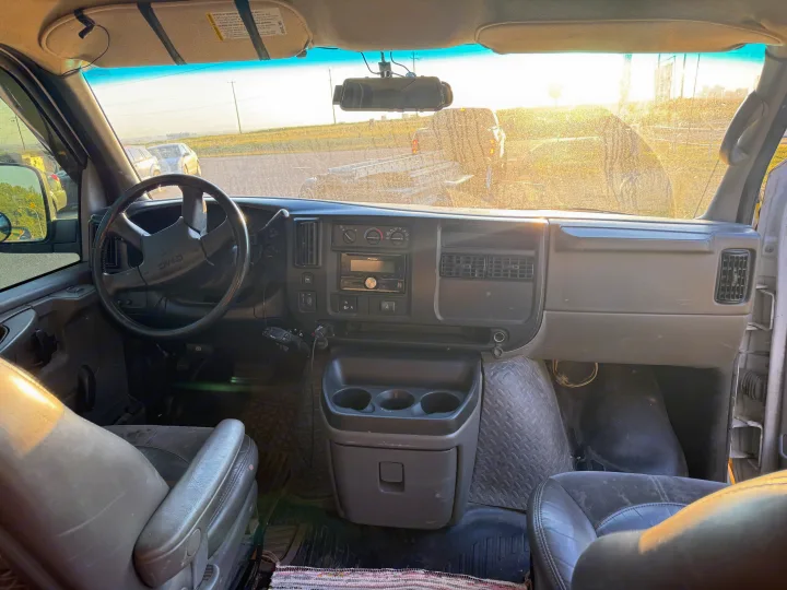 Interior view of a spacious RV rental, showing the driver's seat, dashboard with radio, and steering wheel. Bright sun outside.. Gmc Savanna 2006