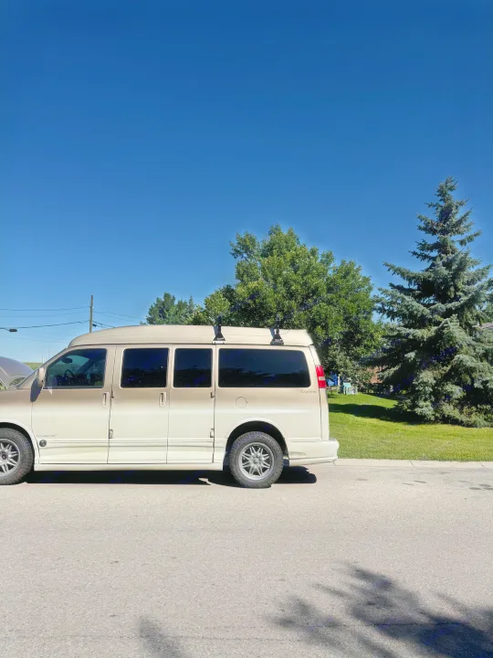 A two-tone conversion van, like an RV rental, is parked on a sunny street with its hood open, ready for travel.. Chevrolet Express Explorer AWD 2007
