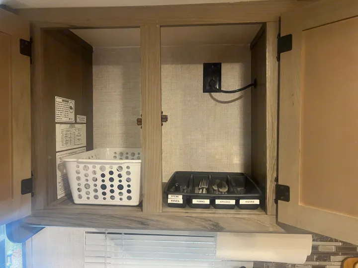 RV rental kitchen cabinet, organized with a cutlery tray (labeled knives, forks, spoons) & storage basket.. Gulf Stream Ameri-Lite Super Lite 2021