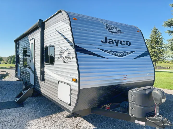 Grey Jayco travel trailer, perfect for an RV rental. Ready for camping trips under a bright blue sky.. Jayco Jay Flight 2021