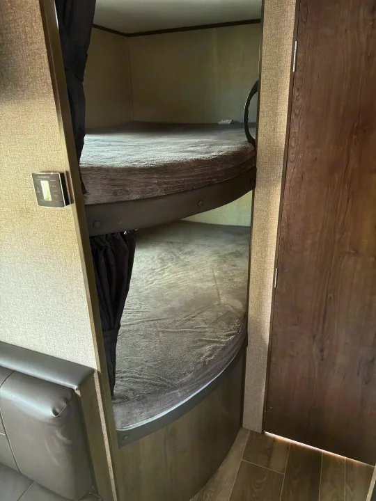 Cozy bunk beds in an RV rental, featuring grey mattresses, curved frames, and Dometic controls.. Jayco Jay Flight 2021