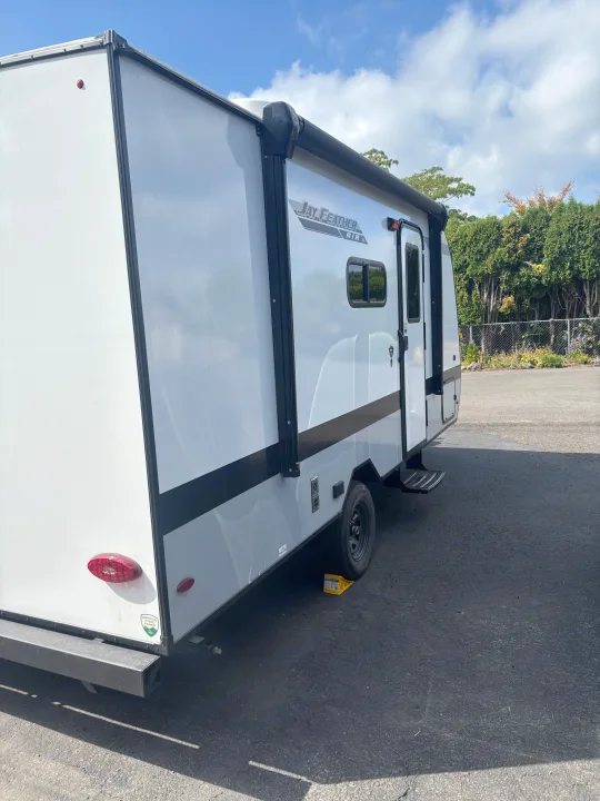 Side view of a white Jay Feather Air SL travel trailer, parked and ready for your RV rental getaway. Features awning & steps.. Jayco Jay Feather Air 2025