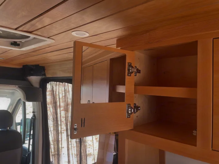 RV rental interior with beautiful wood paneling & functional cabinets. Open cabinet reveals storage & handy mirror.. Dodge 1500 2018