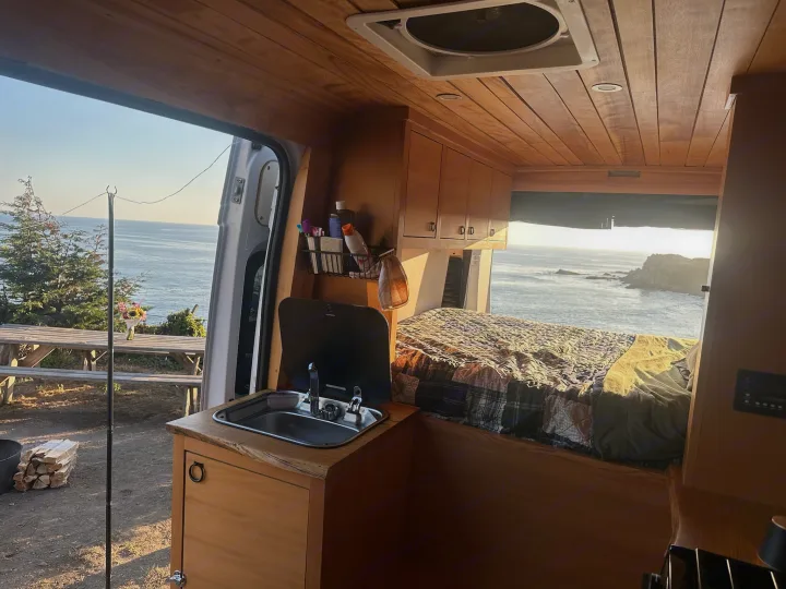 Experience stunning ocean views from this cozy RV rental's custom wood interior, complete with a bed and kitchenette for serene van life.. Dodge 1500 2018