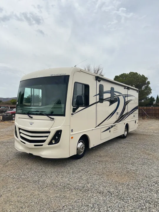 This clean Fleetwood Flair rv rental motorhome sits on a gravel lot under an overcast sky, ready for your next trip.. Flair-Fleetwood Flair-Fleetwood Motorhome 2020