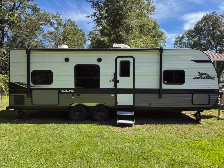 Spacious Jay Flight SLX travel trailer, ideal for an RV rental, parked on green grass with trees under a blue sky.. Jayco Jay Flight SLX 2024