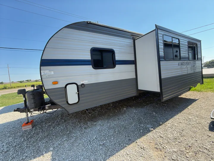 Explore the open road with this Kingsport travel trailer, ideal for your next RV rental. Parked on a gravel lot with its slide-out open.. Gulf Stream Kingsport 2021