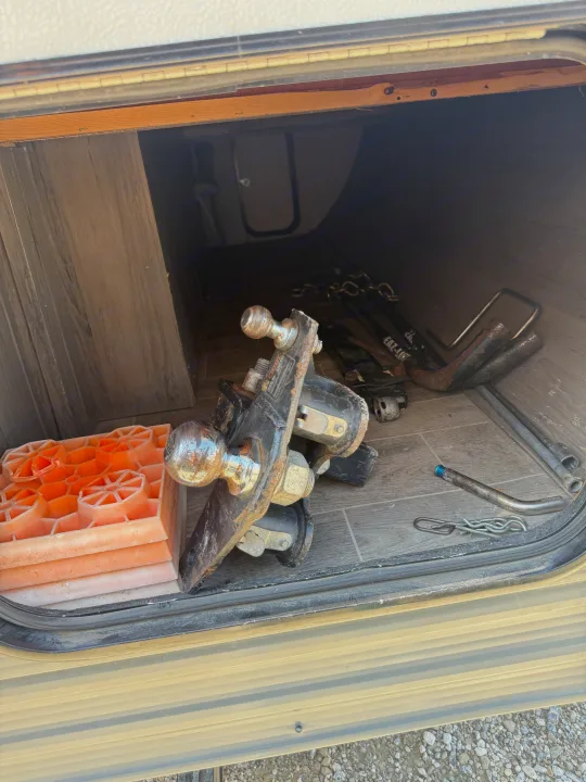 Inside an RV rental's storage compartment: towing hitch, orange leveling blocks, and essential tools.. Gulf Stream Kingsport 2021