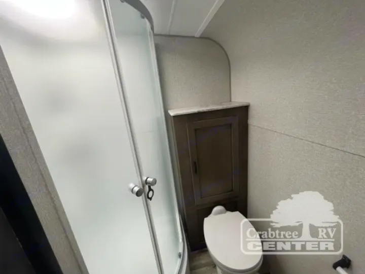 RV rental bathroom featuring a compact, frosted glass shower, a toilet, and a small storage cabinet.. Venture Sonic 190VRB 2022