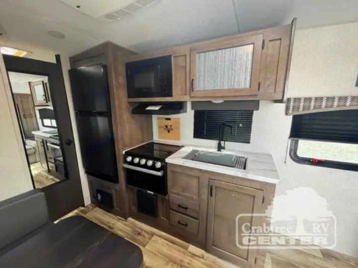 An RV rental's cozy kitchen and dining area. Includes stove, microwave, fridge, and sink. Ready for travel adventures!. Venture Sonic 190VRB 2022