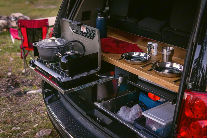 This RV rental's clever tailgate kitchen boasts a stove with a pot/kettle, pans, and storage, perfect for outdoor cooking.. Dodge Converted Dodge Caravan 2020