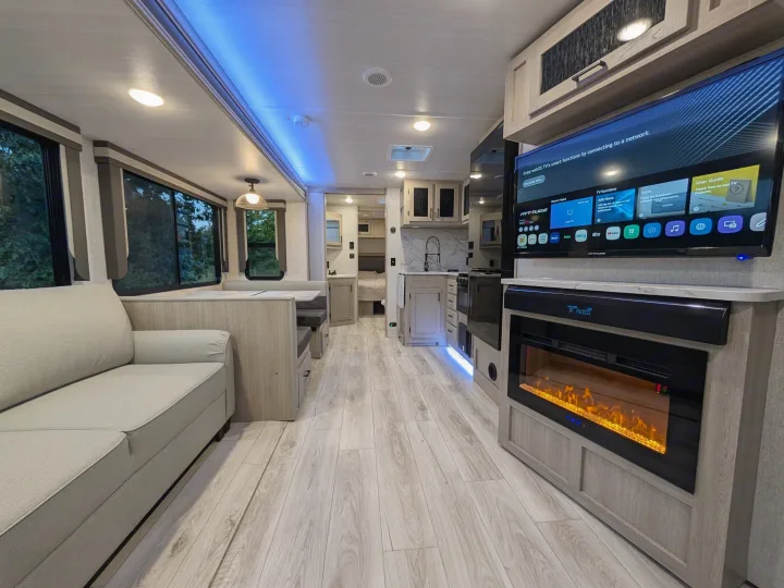 Modern RV rental interior with a comfy living area, kitchen, large smart TV, and an electric fireplace, offering a homey feel.. Forest River Alta 2850KRL 2025