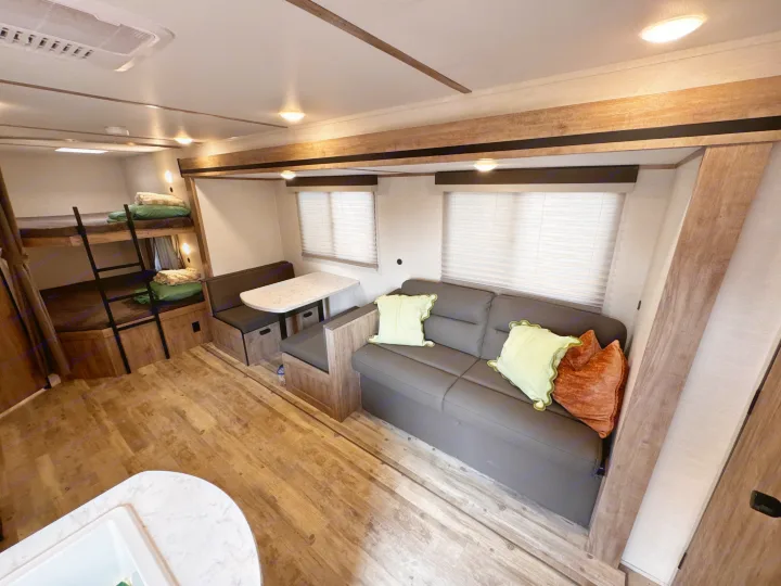 Spacious RV rental interior featuring bunk beds, a dinette, and a sofa, ideal for comfortable travel adventures.. Gulf Stream Enlighten 2025
