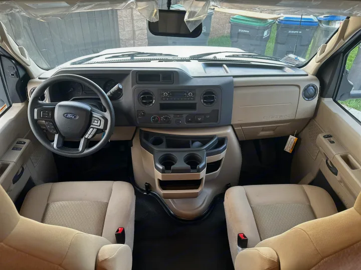 Inside this clean rv rental: Ford dashboard, steering wheel, front seats, and center console with cupholders.. JAYCO REDHAWK SE 22TF 2025