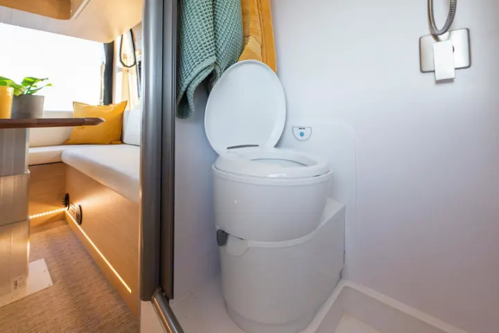 This RV rental features a bright, compact bathroom with a portable toilet, shower, and an inviting interior living space.. Noovo Plus 2025