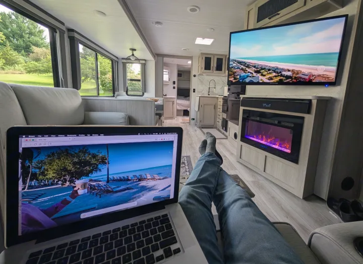 Relaxing in a modern RV rental, enjoying virtual beach views on laptop and TV, with an electric fireplace for ambiance.. Forest River Alta 2850KRL 2025