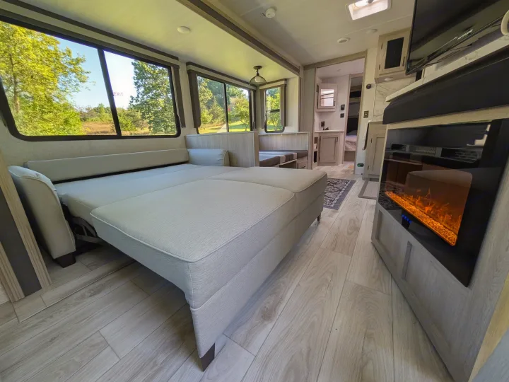 Spacious RV rental living area featuring a pulled-out sofa bed, scenic windows, and an electric fireplace.. Forest River Alta 2850KRL 2025