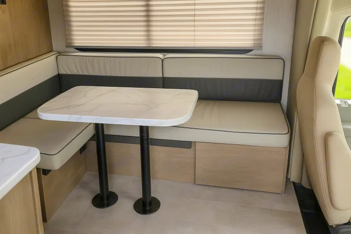 Modern RV rental dinette featuring a U-shaped bench with two-tone cushions, a marble-patterned table, and built-in storage.. Coachman Freelander 22 XG 2023