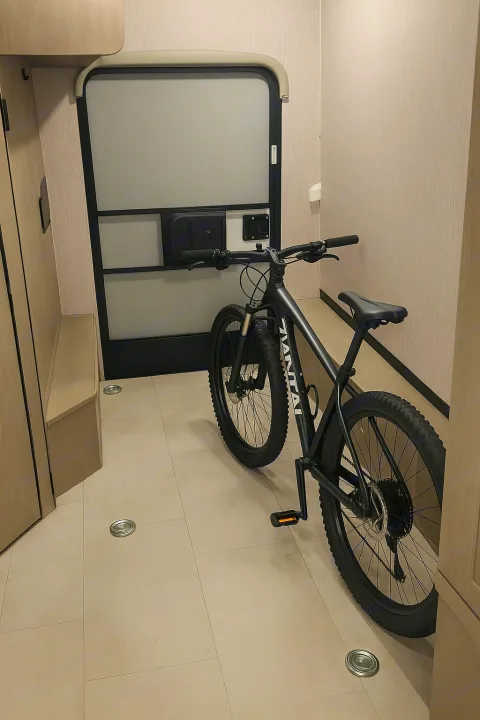 Black mountain bike parked inside a modern **rv rental**. Features a light interior, rear door, and built-in bench storage.. Coachman Freelander 22 XG 2023