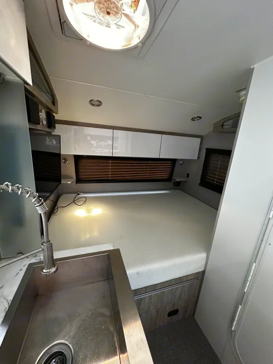 Spacious RV rental interior with a cozy bed, kitchen sink, overhead cabinets, and ceiling fan, perfect for travel.. InTech RV Sol 2023