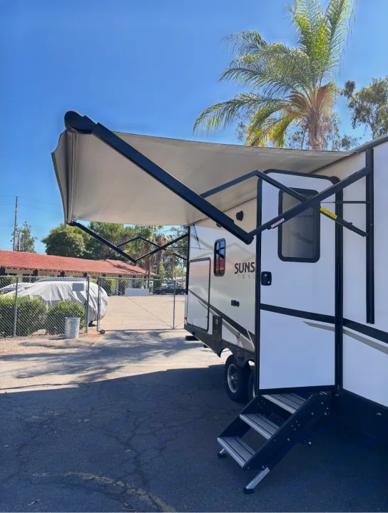 This spacious RV rental, a white travel trailer with an extended awning and entry steps, is ready for your next adventure.. Crossroads RV Sunset Trail Super Lite 2022