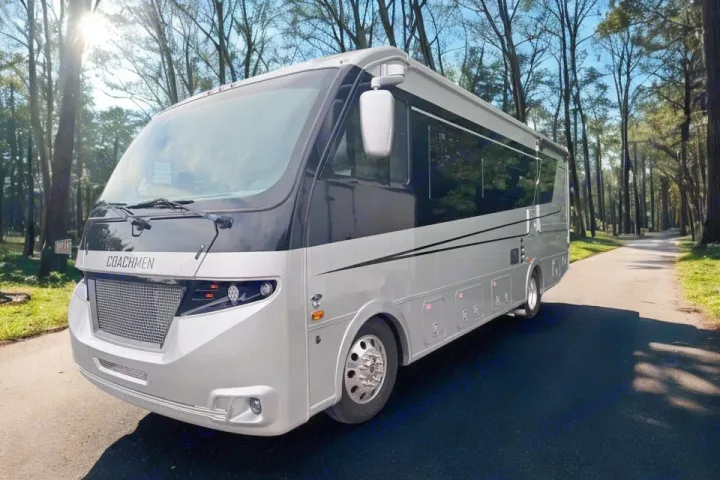 A sleek, silver and black Coachmen RV rental is parked on a tree-lined road, ready for your next adventure.. Coachmen Euro 2025