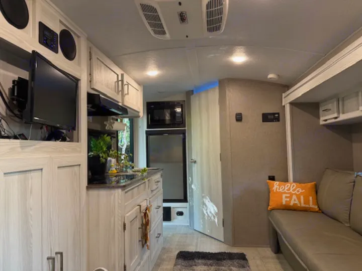 Cozy RV rental interior featuring a full kitchen, sofa, and TV. Ideal for road trips and camping.. Forest River Rockwood Geo Pro 2021