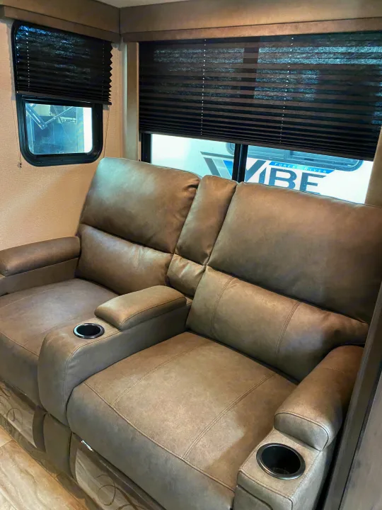 Cozy RV rental living space featuring two grey upholstered recliners with cup holders and privacy blinds.. Grand Design Transcend Xplor 2022