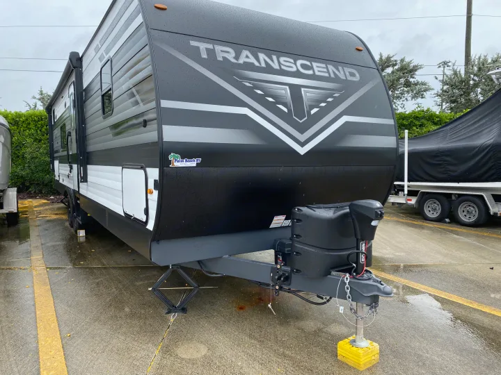 Grand Design Transcend RV rental, a sleek black travel trailer parked on a wet lot, ready for your next adventure.. Grand Design Transcend Xplor 2022