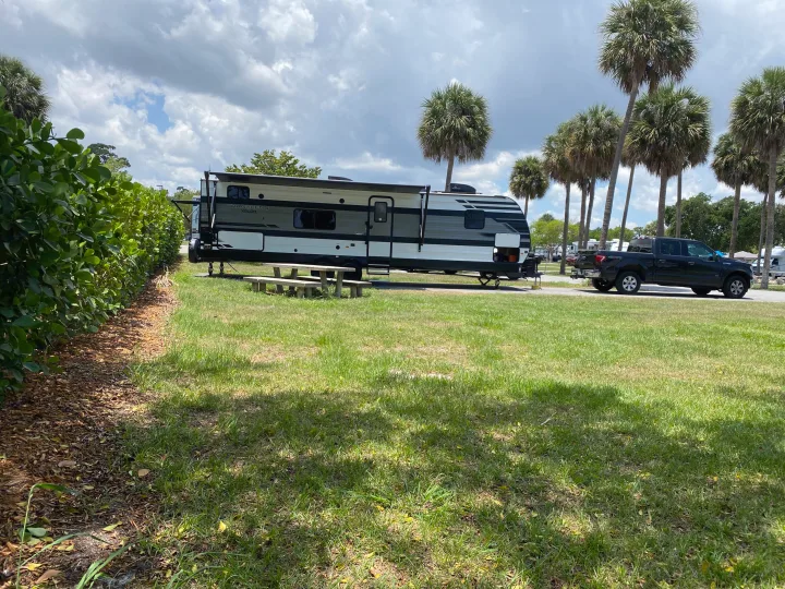 Enjoy your rv rental! A Transcend Xplor travel trailer is parked at a scenic campground site with a picnic table, truck, and palm trees.. Grand Design Transcend Xplor 2022