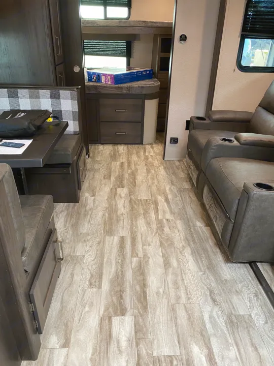 Inside an RV rental, showing bunk beds, a dinette, theater seating, and light wood-look flooring.. Grand Design Transcend Xplor 2022