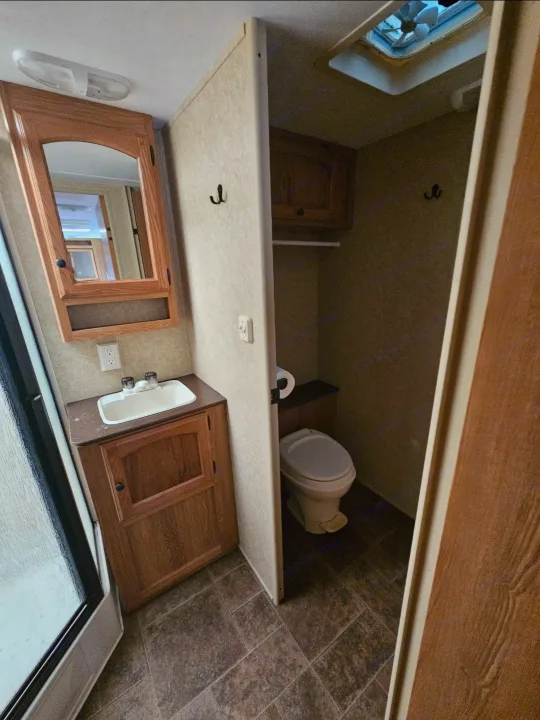 RV rental bathroom: sink, wood vanity, mirrored cabinet, and a toilet in its own space. Shower enclosure is on the left.. Dutchmen Classic 2011