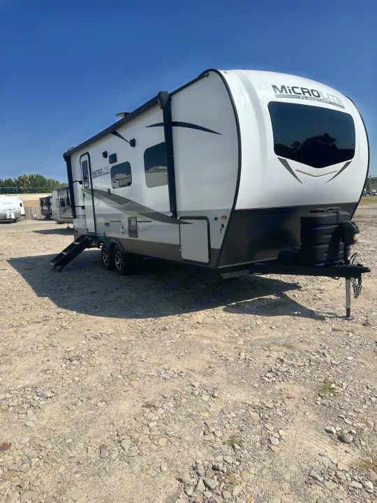 White Micro Lite Flagstaff travel trailer, perfect for rv rental. Parked on a sunny gravel lot, ready for your outdoor adventures.. Forest River Flagstaff Micro Lite 2023