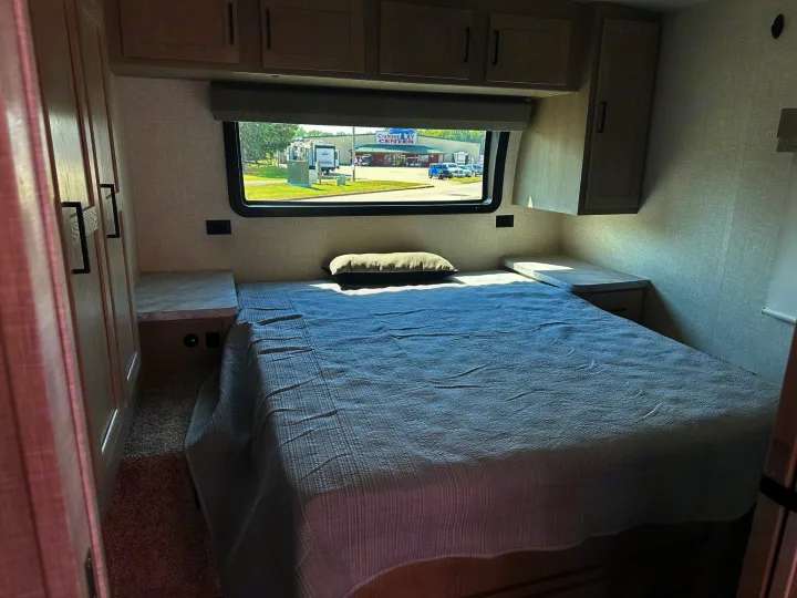 Cozy RV rental bedroom featuring a bed, storage, and window overlooking Crabtree RV Center. Ideal for your next journey.. Forest River Flagstaff Micro Lite 2023