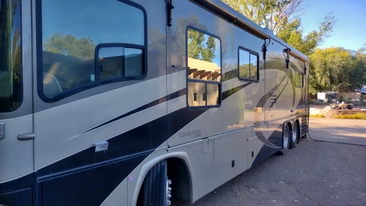 Luxury Country Coach motorhome, beige & black, side view, parked outdoors. Book this rv rental for your next adventure.. Country Coach Allure 470 2005