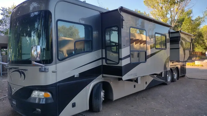 Spacious grey and black motorhome, ideal for an RV rental adventure, with slide-outs extended in a sunny outdoor setting.. Country Coach Allure 470 2005