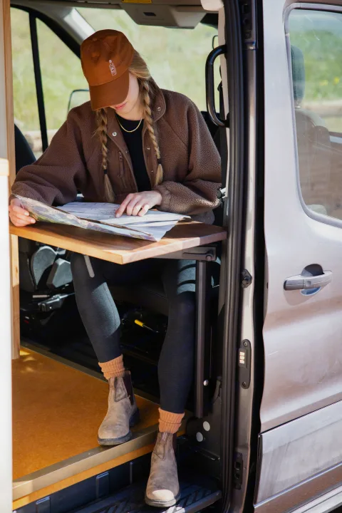 Planning your next adventure! Woman studies a map inside a cozy RV rental van, ready for the open road.. Ford Transit 2023
