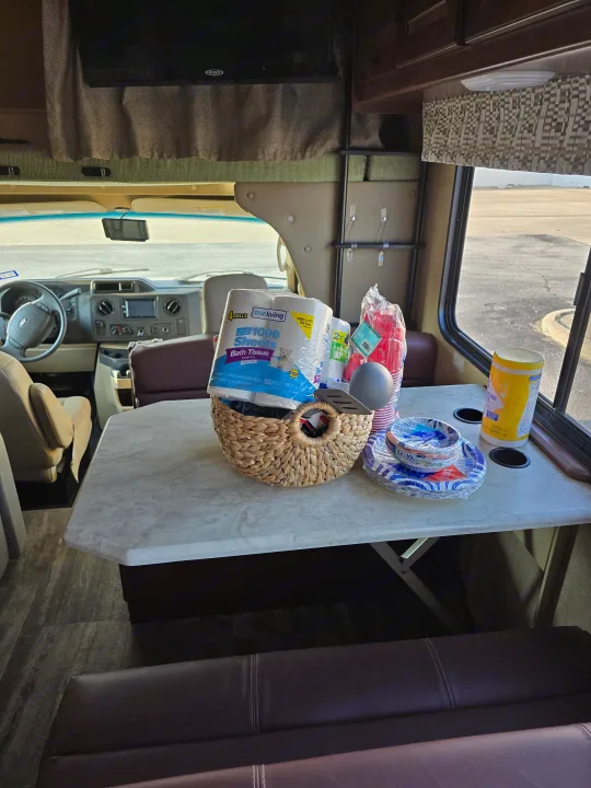 Inside an RV rental, a table holds essential supplies like bath tissue, paper plates, cups, and cleaning wipes, ready for a trip.. Forest River Sunseeker 2016