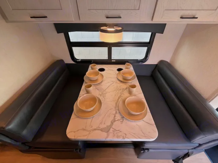 Spacious RV rental dinette with a marble-look table and comfy black benches, ideal for dining in your camper.. Nexus Viper 2026