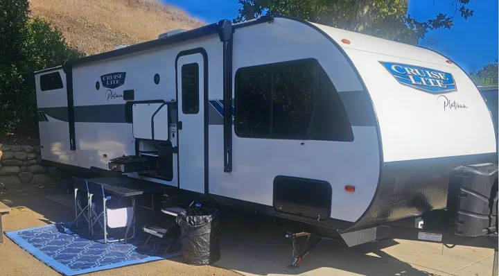 White Cruise Lite Platinum RV rental set up for outdoor living with a blue mat & chairs. Perfect for your next travel adventure.. Salem Cruise LIte Platinum 28VBLX 2024