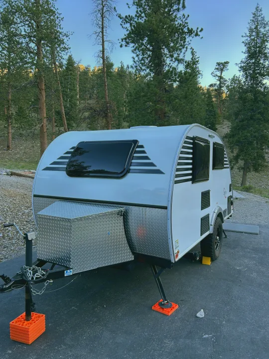 A compact rv rental, a white teardrop trailer, parked in a tranquil pine forest campsite for a nature getaway.. Xtreme Outdoors Xtreme Outdoors Trailer 2022